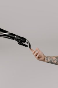 Close-up of a prosthetic arm and a human hand reaching towards each other in harmony.