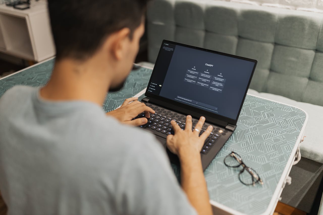 A man working on a laptop displaying ChatGPTs interface in an indoor setting.